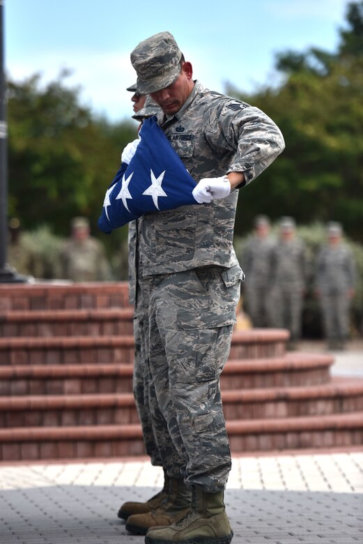 U.S. Air Force Staff Sgt. Greg Helms, Goodfellow Honor Guard member, smoothes the flag after folding during the special retreat ceremony held at the flagpole in front of the Norma Brown building on Goodfellow Air Force Base, Texas, Sept. 11, 2019. Retreat is a ceremony where the flag is lowered, folded and secured for the night before being taken out and flown the next day. (U.S. Air Force photo by Senior Airman Seraiah Wolf/Released)