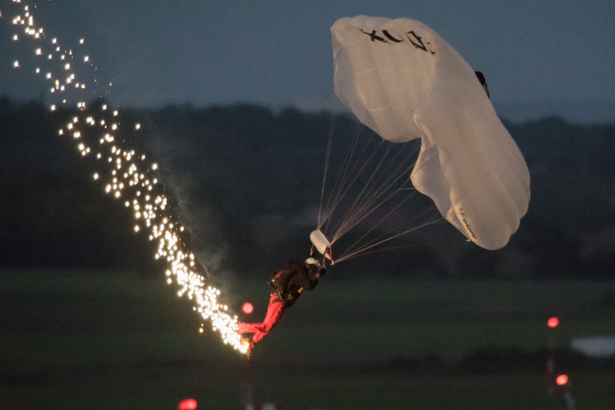 A member of the U.S. Army Special Operations Command Black Daggers Parachute Demonstration Team lands after a twilight jump at the 2019 Thunder Over Dover Air Show, Sept. 13, 2019, at Dover Air Force Base, Del. The team performed several jumps during the event to demonstrate various skills. (U.S. Air Force photo by Mauricio Campino)