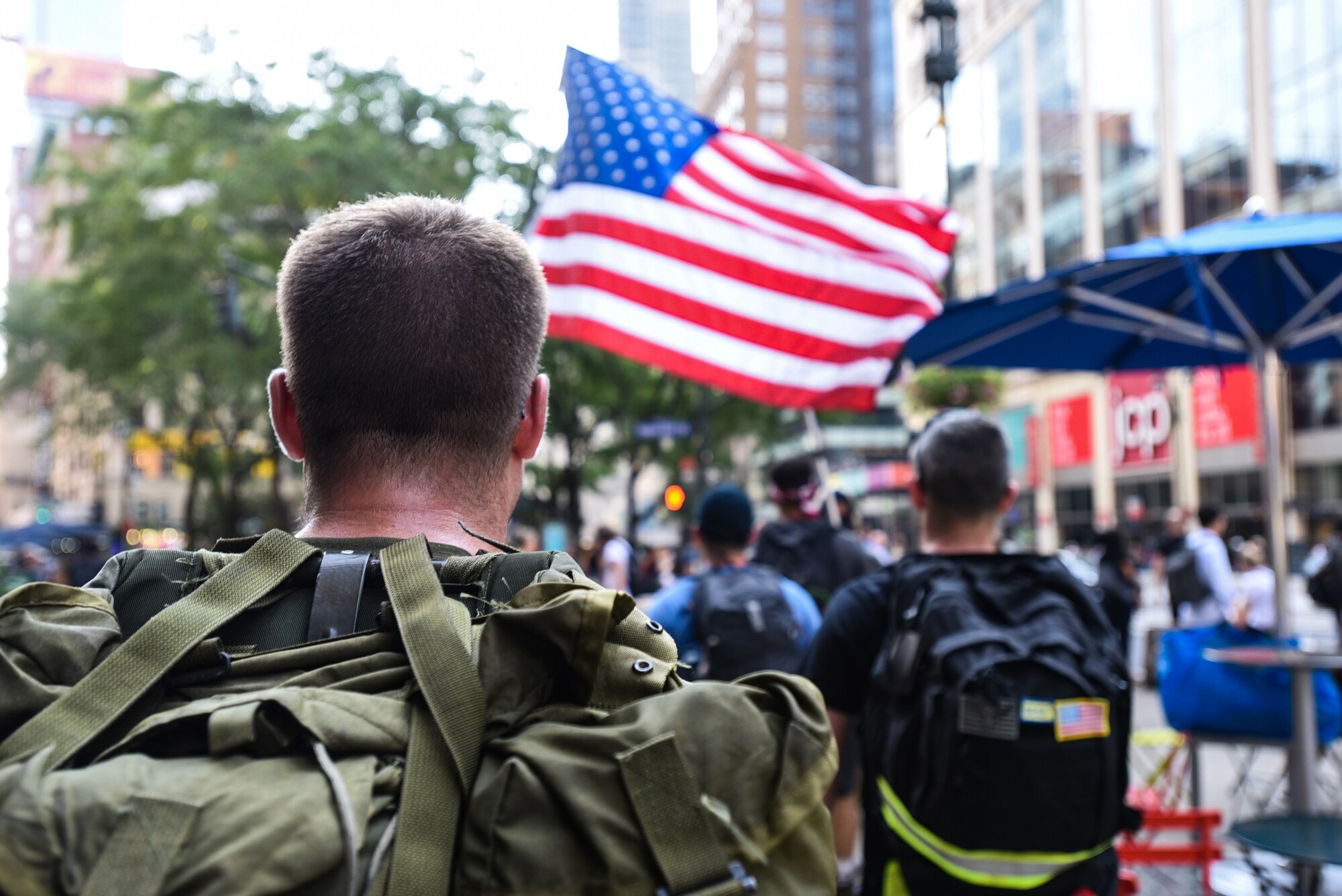 Tech. Sgt. Joshua Schmitz, 818th Mobility Support Advisory Squadron survival, evasion, resistance and escape specialist, looks at the American flag while marching towards ground zero in New York City Sept. 11, 2019. Volunteers participated in a 100 mile ruck march from Joint Base McGuire-Dix-Lakehurst, New Jersey to the 9/11 Memorial in remembrance of the attacks 18 years ago.   Throughout the 100 miles, participants took turns carrying a prisoner of war/missing in action flag along with an American flag that served in Afghanistan to commemorate the individuals who lost their lives during the attacks. (U.S. Air Force photo by Airman 1st Class Ariel Owings)