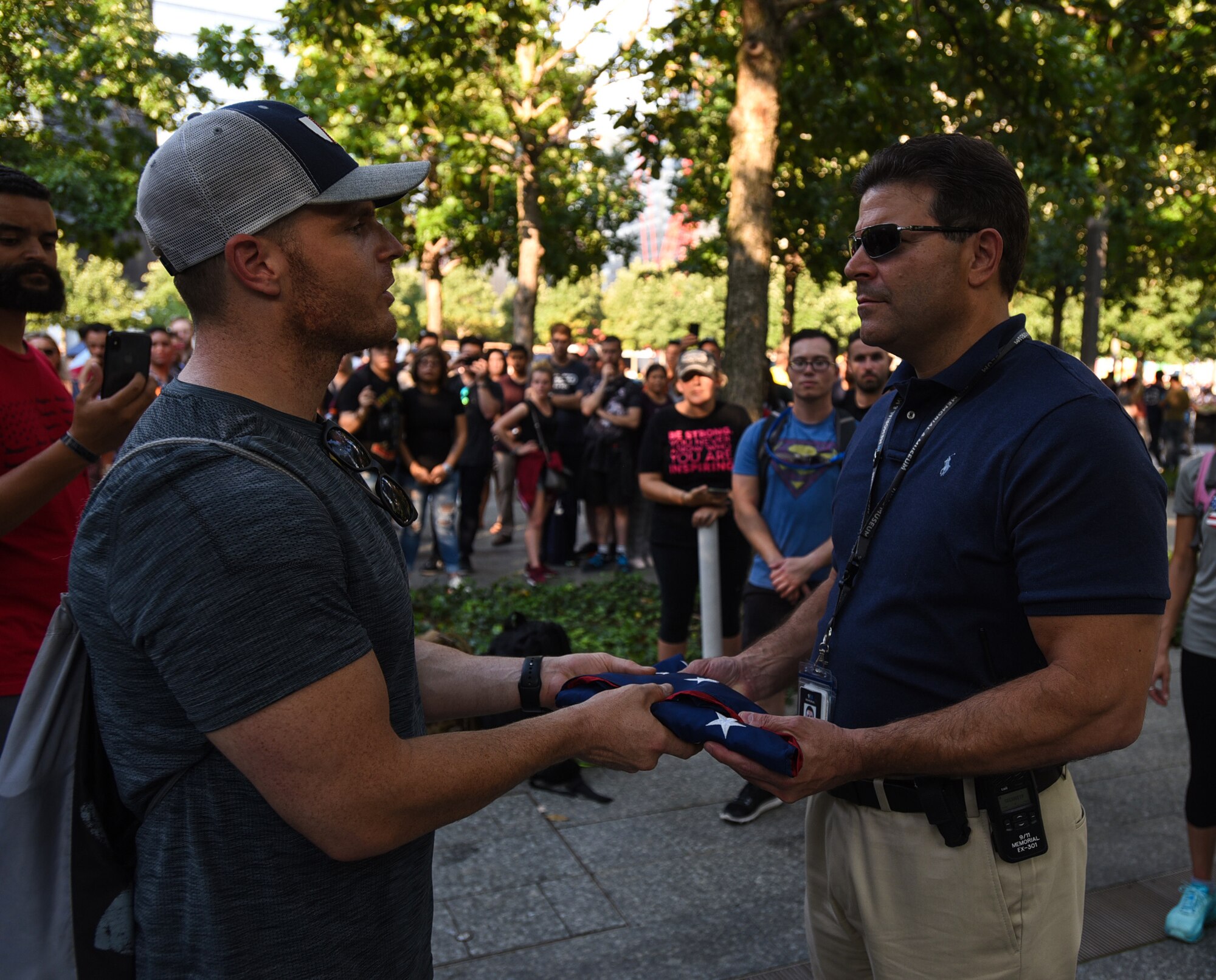U.S. Air Force Maj. Jon Leetch, Columbus Air Force Base, Miss. 41st Flying Training Squadron instructor pilot, hands off an American flag to Paul Vorbeck, 9/11 Memorial and Museum director of security, after the 100 mile ruck from Joint Base McGuire-Dix-Lakehurst, New Jersey to New York City Sept. 11, 2019. Throughout the 100 miles, participants took turns carrying a prisoner of war/missing in action flag along with an American flag that served in Afghanistan to commemorate the individuals who lost their lives during the attacks. (U.S. Air Force photo by Airman 1st Class Ariel Owings)