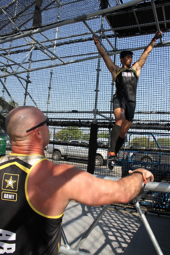 U.S. Army 2nd Lt. Chris Gabayan crosses lower level bars in "Alacatraz" while Sgt. 1st Class Aaron Martin cheers him on during the 2019 Alpha Warrior Inter-Service Battle Sept. 14, 2019, at Retama Park, Selma, Texas. Alcatraz  is the last of more than 30 obstacles on the course. At the end of this year's competition, the U.S. Air Force earned a repeat victory over the Army and the U.S. Navy. (U.S. Air Force photo by Debbie Aragon)