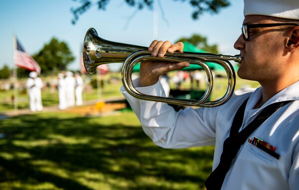 A sailor plays a bugle.