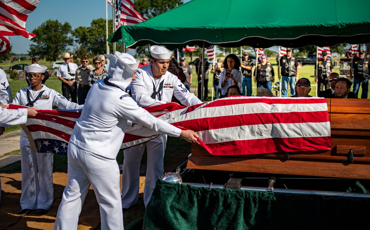 Sailors remove a flag from a casket.