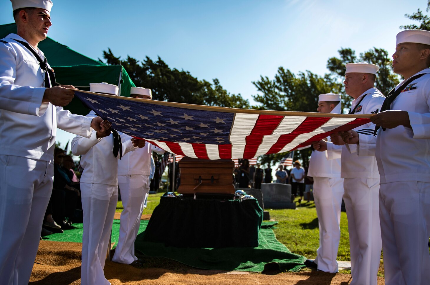 Sailors prepare to fold a flag.