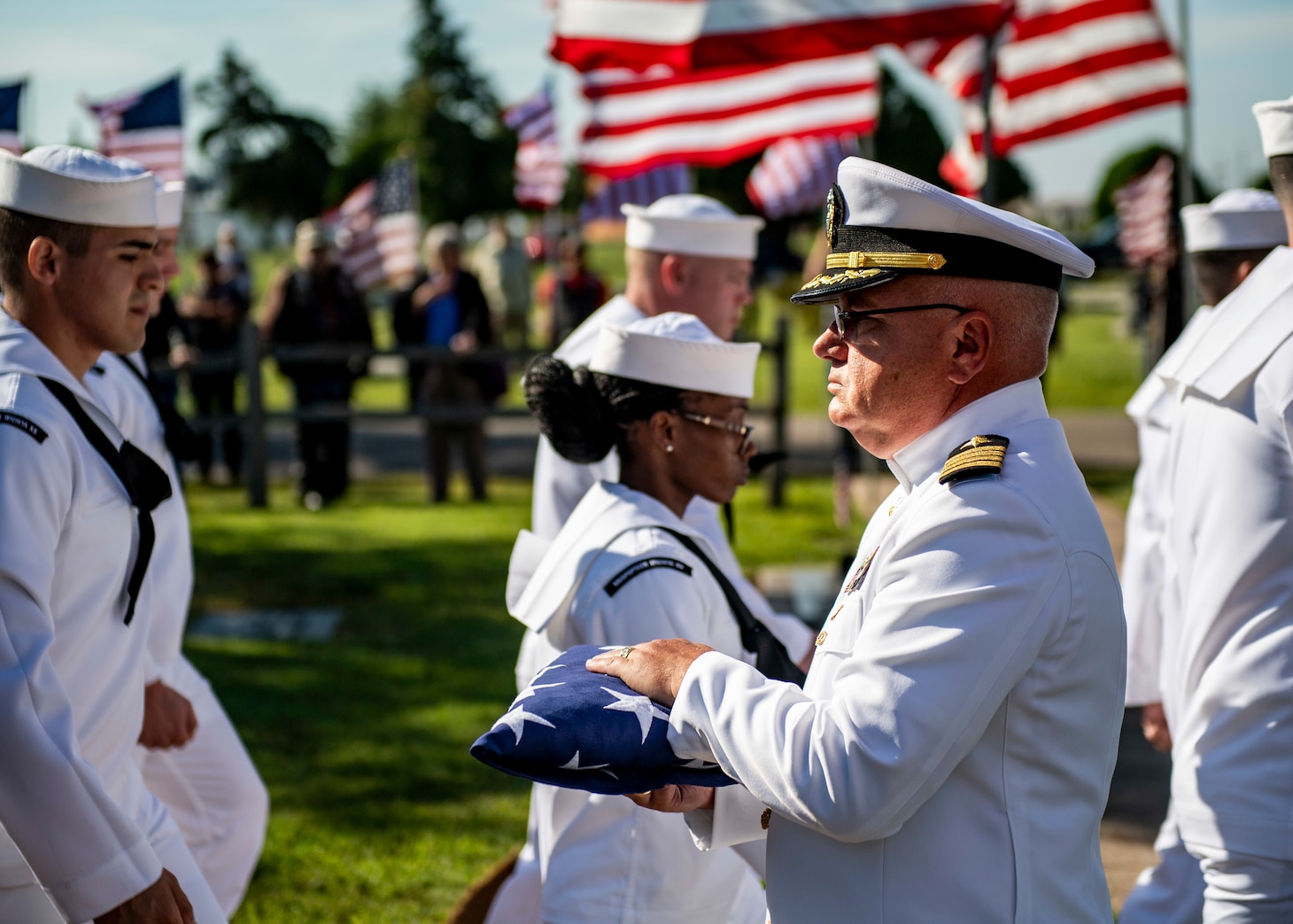 A sailor presents a folded flag.
