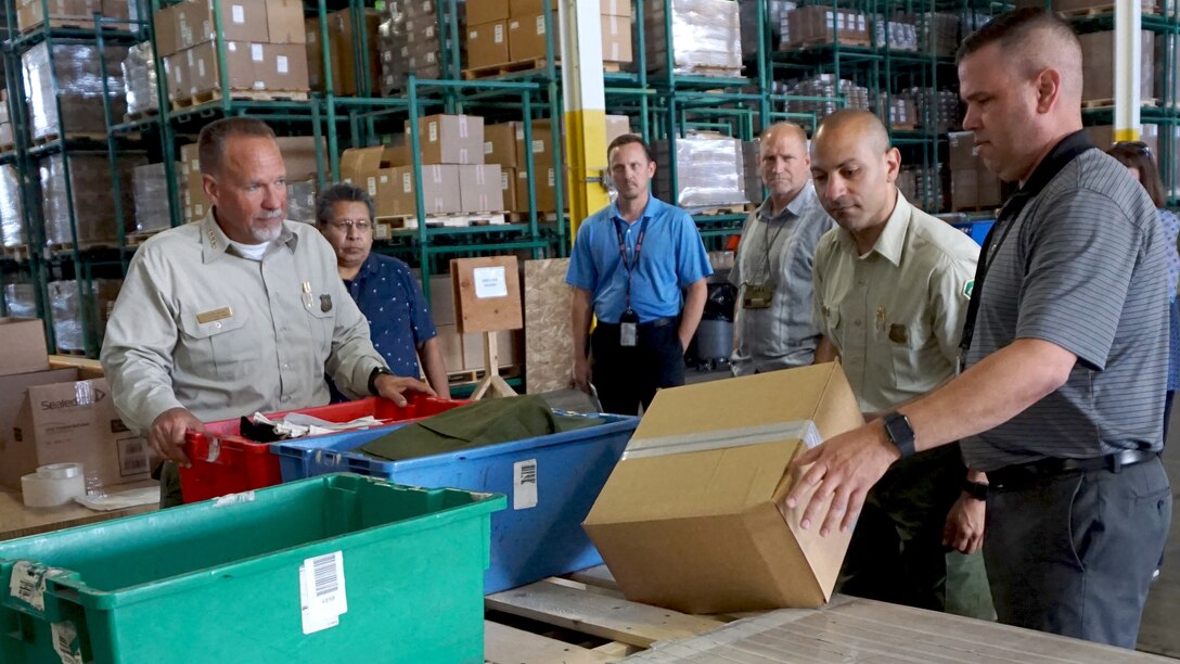 Warehouse workers inspect boxes and bins containing wildland firefighting equipment