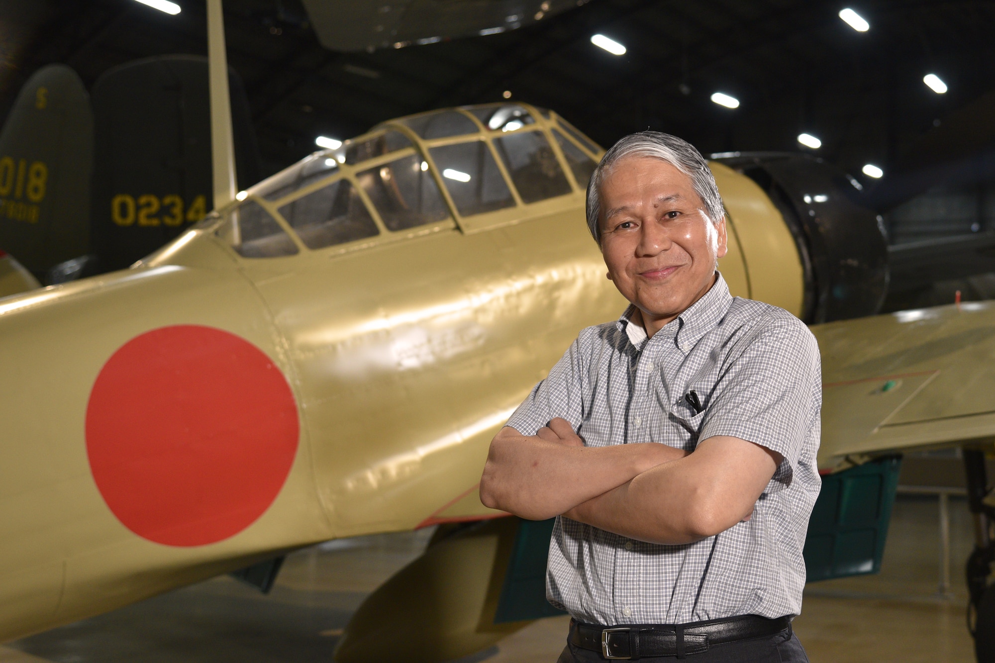 Photo of two people at Japanese Zero aircraft from World War II.