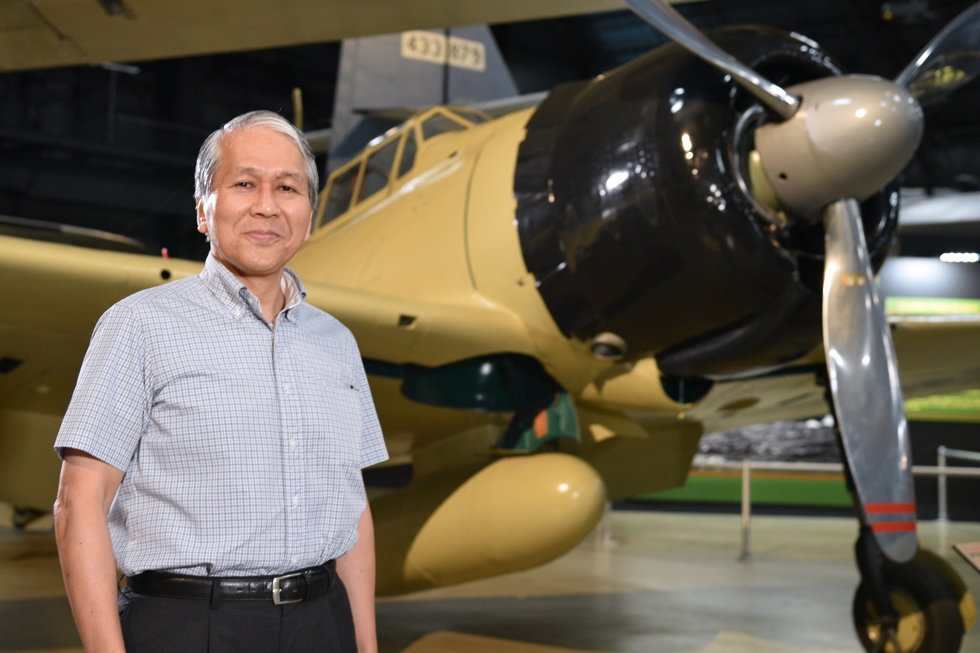 Photo of two people at Japanese Zero aircraft from World War II.