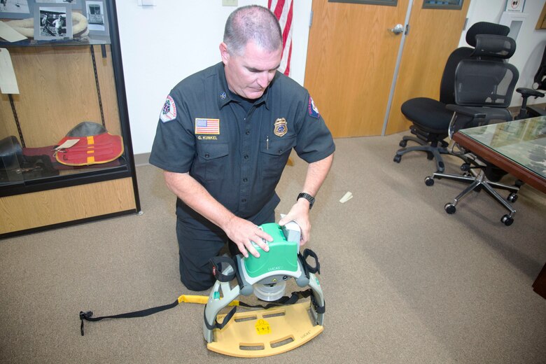Assistant Fire Chief Greg Kunkel, Emergency Medical Services supervisor, MCLB Fire Department, slides the rechargeable lithium ion battery pack into a slot on the Lucas 2 automatic chest compression device. The yellow board at the bottom goes under the gurnery or board the patient is strapped to while the green piston goes over the top position on the sternum and delivers 110 compressions a minute, the CPR standard requirement. The $15,000 Lucas 2 can also be plugged into the ambulance power through and invertor port so it does not rely on the device battery