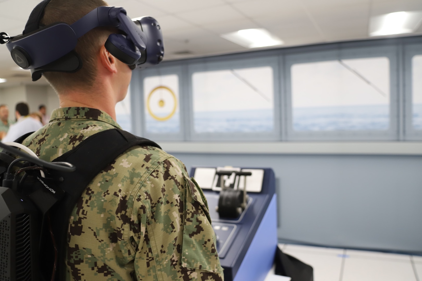 IMAGE: A Sailor from Tactical Training Group Atlantic stands in the helm position during an Advanced Navigation Team Shipboard Simulation Phase 1 system scenario in the command’s Naval Simulation Center. The Sailor is observing the real world through the augmented reality headset.