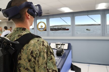 IMAGE: A Sailor from Tactical Training Group Atlantic stands in the helm position during an Advanced Navigation Team Shipboard Simulation Phase 1 system scenario in the command’s Naval Simulation Center. The Sailor is observing the simulated world through the augmented reality headset.