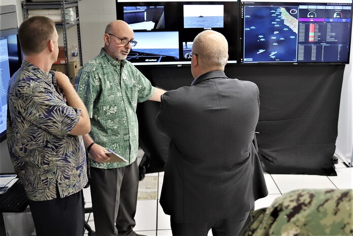 IMAGE: Glenn White (center), Office of Naval Research, discusses Mentor Station “real time” data analytics to John Fiore, Naval Surface Warfare Center Dahlgren Division technical director. The briefing occurred during an Advanced Navigation Team Shipboard Simulation Phase 1 system demonstration in the command’s Naval Simulation Center.