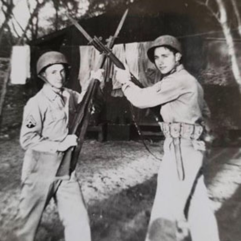 Two soldiers pose for a photo with their rifles crossed