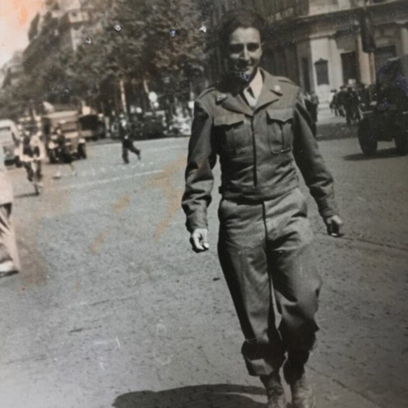 Historic photo of a manan in a U.S. Army uniform walking down a street.
