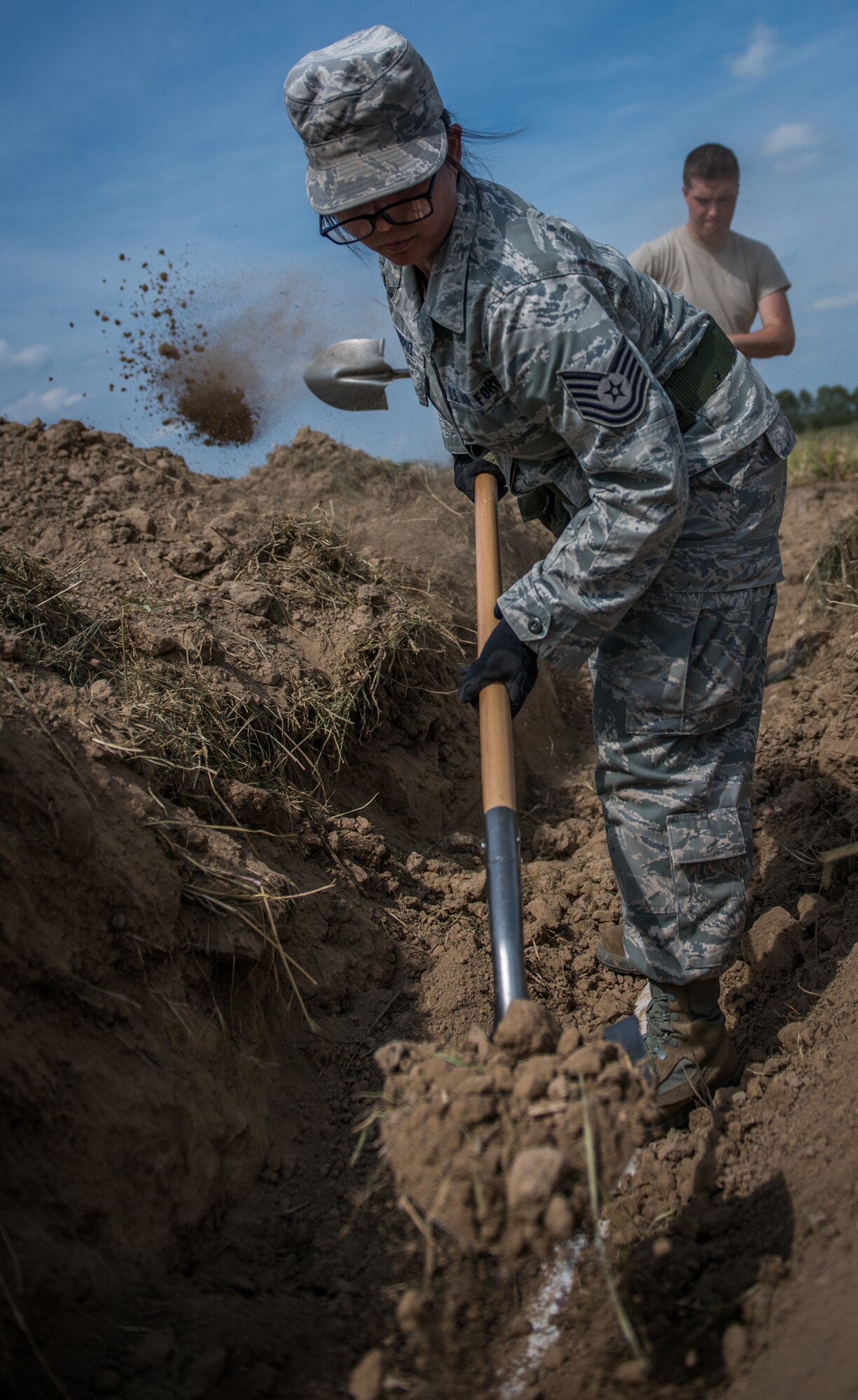 932nd Civil Engineer technician, Tech. Sgt. Tiana Corpuz, with help from fellow Reserve Citizen Airman Senior Airman Alex Ravenmeder,  uses a shovel to uncover a plastic pipe simulating a pressurized water-main  during field training, Sept. 10, 2019 at the Sparta National Guard training area, Sparta, Illinois. (U.S. Air Force photo by Master Sgt. Christopher Parr)