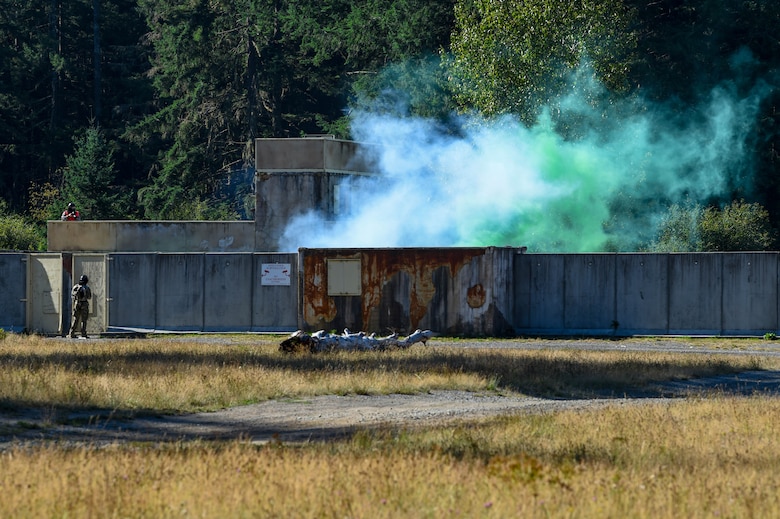 As tactical air control party (TACP) officer candidates head into a mock-deployment tactical village the cadre carrying out the exercise set off M84 stun grenades and simulation tear gas grenades to create a stressful environment in which the candidates are evaluated during TOPT selection course phase II, on Joint Base Lewis-McChord, Wash., Aug. 27, 2019. During this phase of selection, experienced TACP officer and enlisted cadre assess candidates throughout a week during 15 graded events that target the specific personality and character attributes that correlate with success in the TACP community.