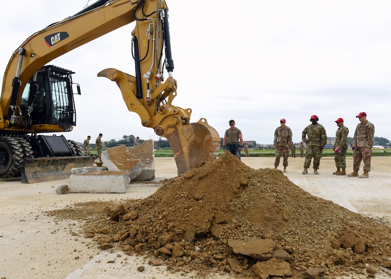 Airmen from the 51st Civil Engineer Squadron and the 554th Rapid Engineer Deployable Heavy Operational Repair Squadron assigned to Andersen Air Force Base, Guam, watch as an excavator rips up a section of concrete during the 51st CES’ biannual rapid airfield damage repair training on Osan Air Base, Republic of Korea, September 12, 2019. This training is designed to demonstrate the squadron’s ability to rapidly repair the airfield after its been damaged. (U.S. Air Force photo by Senior Airman Denise Jenson)