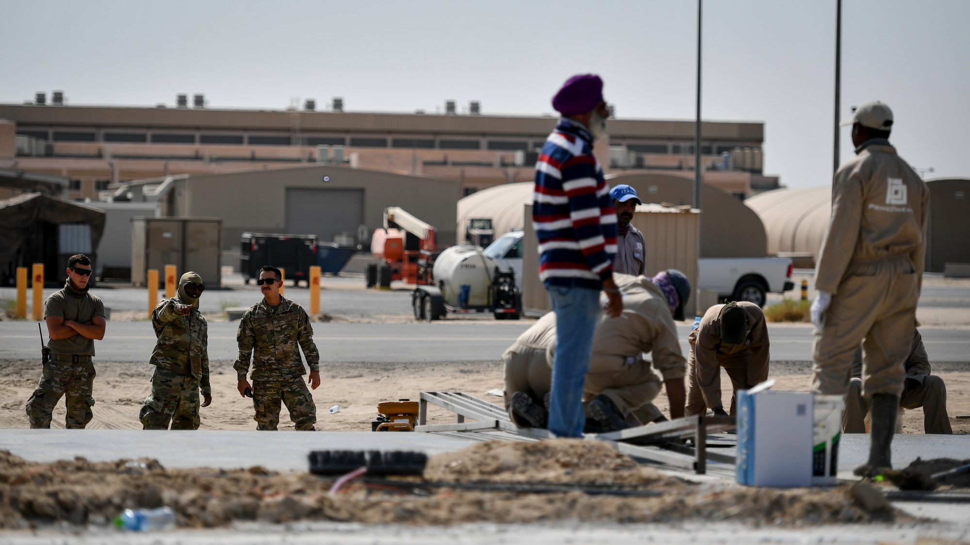 Airmen assigned to the 386th Expeditionary Civil Engineer Squadron observe contractors building an addition to the flightline at Ali Al Salem, Kuwait, Sept. 4, 2019. The force protection flight provides a security buffer between other country nationals such as contractors, their employees and the general base population. Airmen assist and escort OCNs during their duty day, help minimize potential data collection, and ensure the departure of vehicles and personnel once their services are completed for the day. (U.S. Air Force photo by Staff Sgt. Mozer O. Da Cunha)