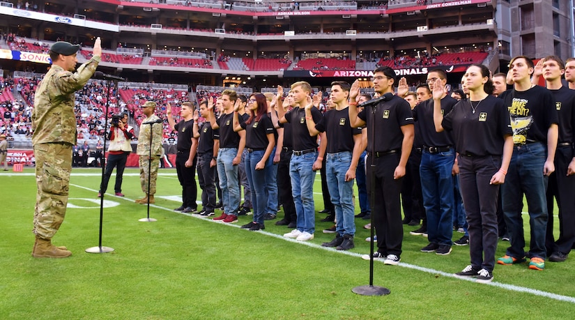 group of young men and women holding up their right hand to take an oath of enlistment.