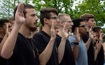 a group of young men and women hold up their right hands to enlist in the United States Army.