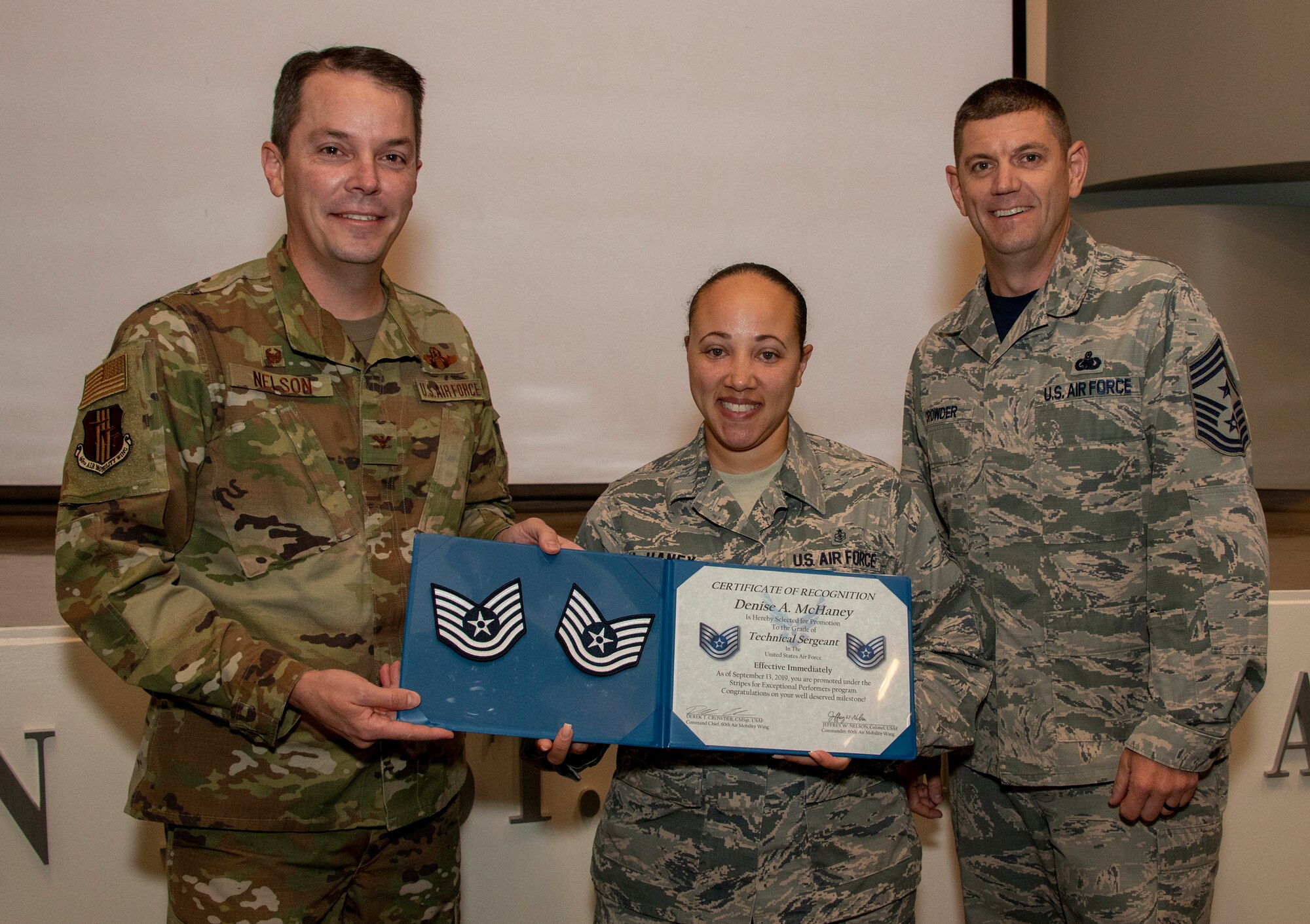 U.S. Air Force Col. Jeffrey Nelson, left, 60th Air Mobility Wing commander, and Chief Master Sgt. Derek Crowder, right, 60th AMW command chief, present Staff Sgt. Denise McHaney, 60th Aerospace Medicine Squadron public health supervisor, with her Stripes for Exceptional Performers certificate for technical sergeant Sept. 13, 2019, at David Grant USAF Medical Center, Travis Air Force Base, California. The STEP promotion program offers commanders a limited opportunity to immediately promote enlisted members to staff sergeant or technical sergeant. (U.S. Air Force photo by Heide Couch)
