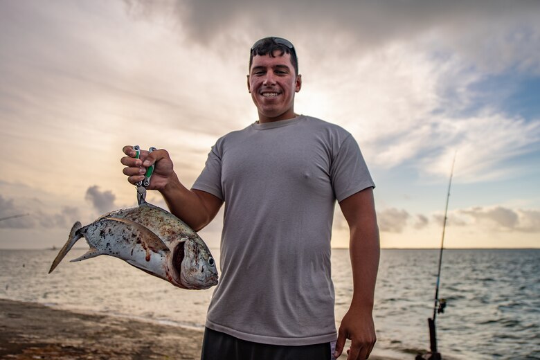 U.S. Air Force Tech. Sgt. Gary Yates, 475th Expeditionary Air Base Squadron air operations noncommissioned officer in charge, poses with a fish he caught at a pier near Camp Simba, Kenya, Aug. 29, 2019. Yates is responsible for managing incoming and outgoing cargo and passengers between Camp Simba and other military installations within the area of responsibility. During his time in Kenya, Yates often wakes up hours before work to go fishing at the pier with his friends. (U.S. Air Force photo by Staff Sgt. Devin Boyer)