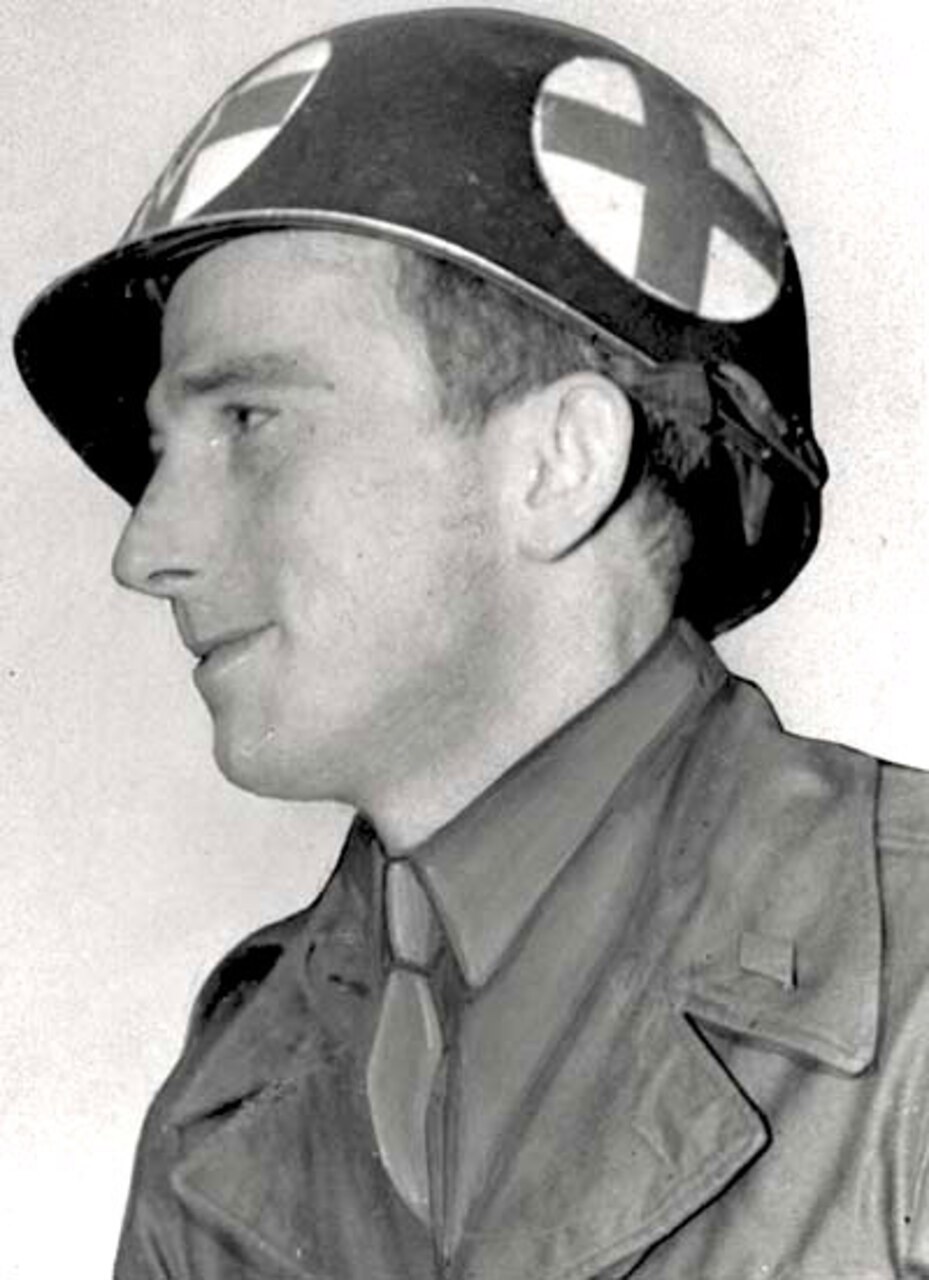 A man wearing a medic's helmet looks left.