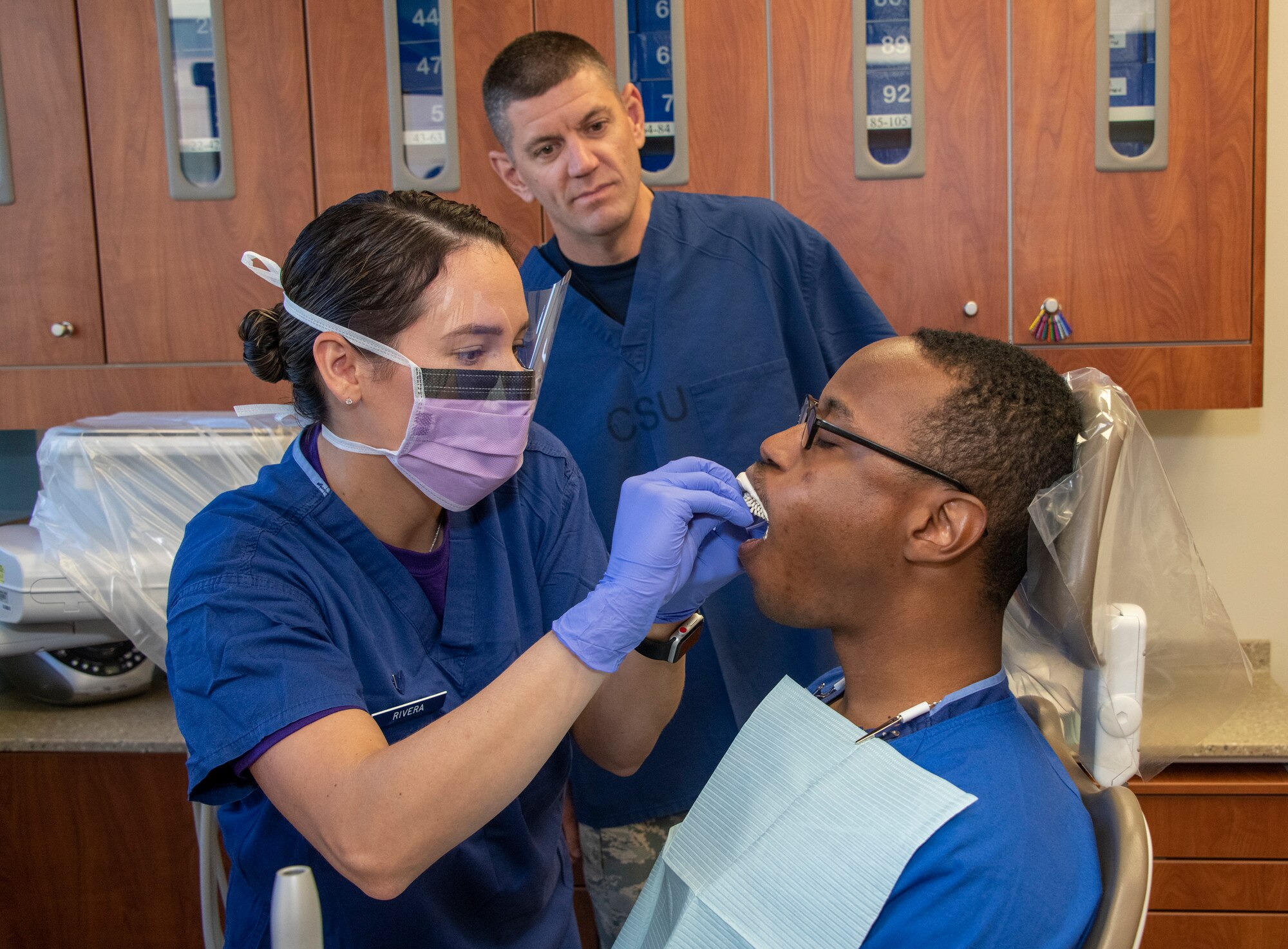 U.S. Air Force Chief Master Sgt. Derek Crowder, 60th Air Mobility Wing command chief watches Senior Airmen Rosemarie Rivera, left, and Keenan Jones, both 60th Dental Squadron dental assistants, demonstrate the procedure of taking a dental impression during Leadership Rounds Sept. 13, 2019, at David Grant USAF Medical Center, Travis Air Force Base, California. The Leadership Rounds program involves wing leadership interacting with Airmen to get a detailed view of each mission performed at Travis AFB. (U.S. Air Force photo by Heide Couch)
