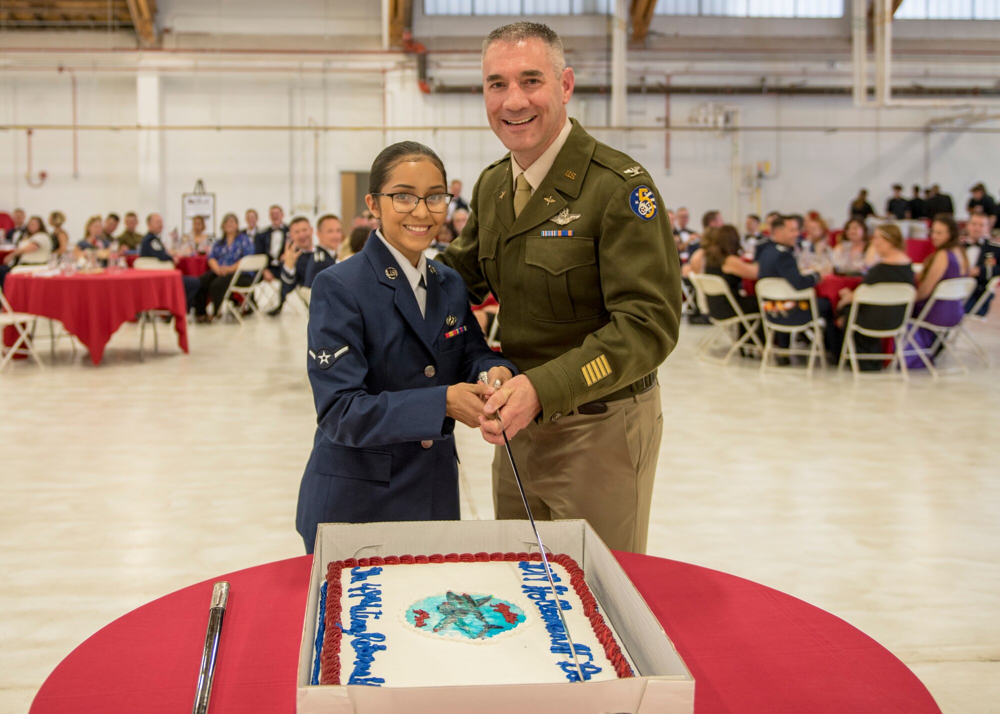 Col. Joseph Campo, 49th Wing commander, and Airman Breauna Sierra, 49th Logistics Readiness Squadron customer service Airman, cut the first piece of cake at the Air Force Ball, Sept. 14, 2019, on Holloman Air Force Base, N.M. At the Air Force Ball, it is tradition for the highest-ranking member and lowest-ranking member to cut the first piece of cake, symbolizing the passing of knowledge and inspiration from one generation to the next. (U.S. Air Force photo by Airman 1st Class Kindra Stewart)