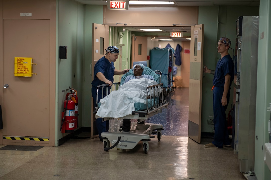 Surgical staff transports a woman into a post-anesthesia care unit.