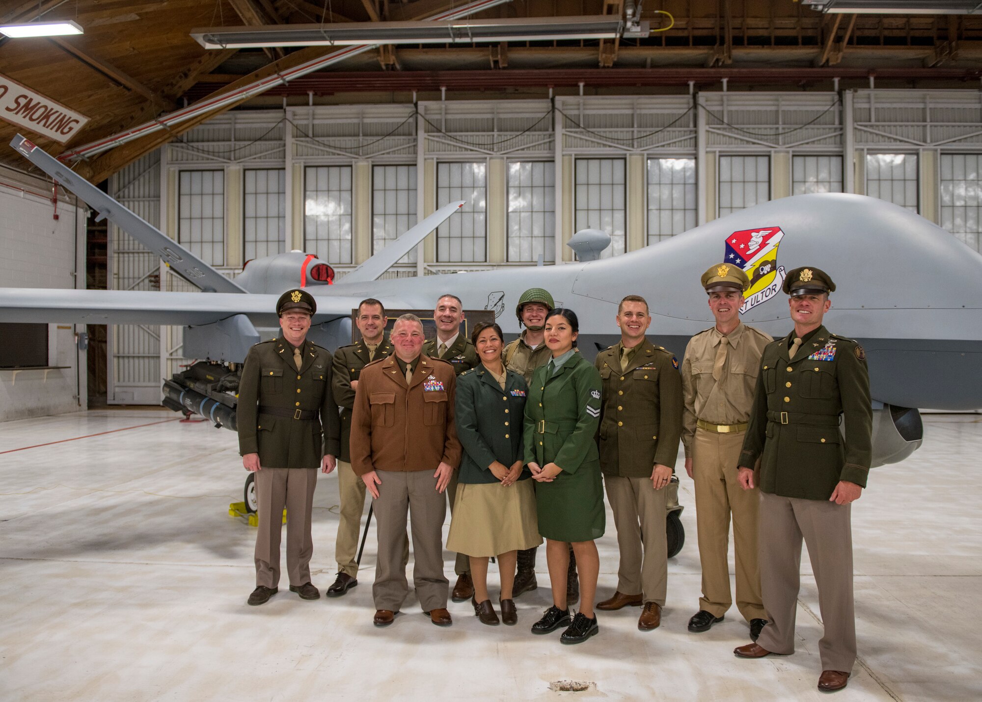 Airmen pose for a photo in front of a MQ-9 Reaper at the Air Force Ball, Sept. 14, 2019, on Holloman Air Force Base, N.M. This year’s ball was themed "The 49th Wing Returns Home" and Airmen were encouraged to dress in uniforms from the Army Air Corps. (U.S. Air Force photo by Airman 1st Class Kindra Stewart)