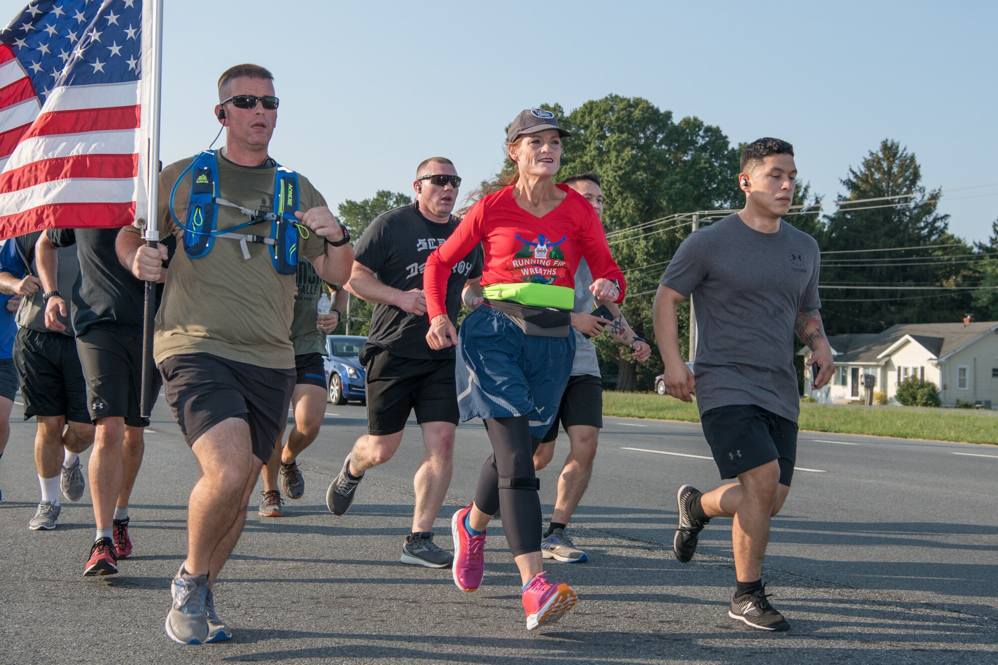 Master Sgt. Trevor Derr, 736th Aircraft Maintenance Squadron C-17 production superintendent (with flag), and Cathy Powers, Gold Star Mother, run alongside members of Team Dover during the “Running Fir Wreaths” campaign Sept. 12, 2019, outside Dover Air Force Base, Del. Powers plans to run 1,000 miles across all 50 states in honor of her son and fallen veterans. (U.S. Air Force Photo by Mauricio Campino)