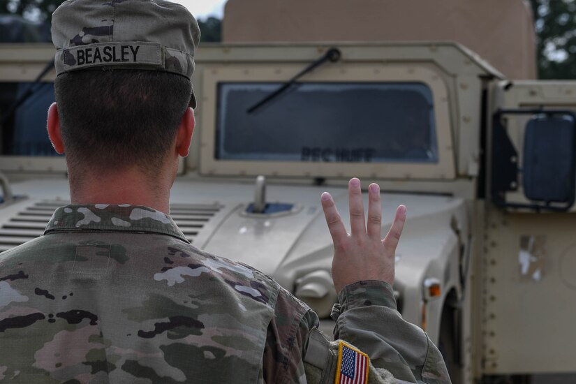 U.S. Army Pfc. Chris Beasely, a wheeled vehicle mechanic with the 597th Transportation Brigade, 832nd Trans. Battalion, 688th Rapid Port Opening Element, gives hand signals to a Humvee driver to test the lights at Joint Base Langley-Eustis, Virginia, Sept. 16, 2019. Ensuring the lights and turn signals work allows the Soldiers to drive on main roads on and off the installation. (U.S. Air Force photo by Senior Airman Derek Seifert)