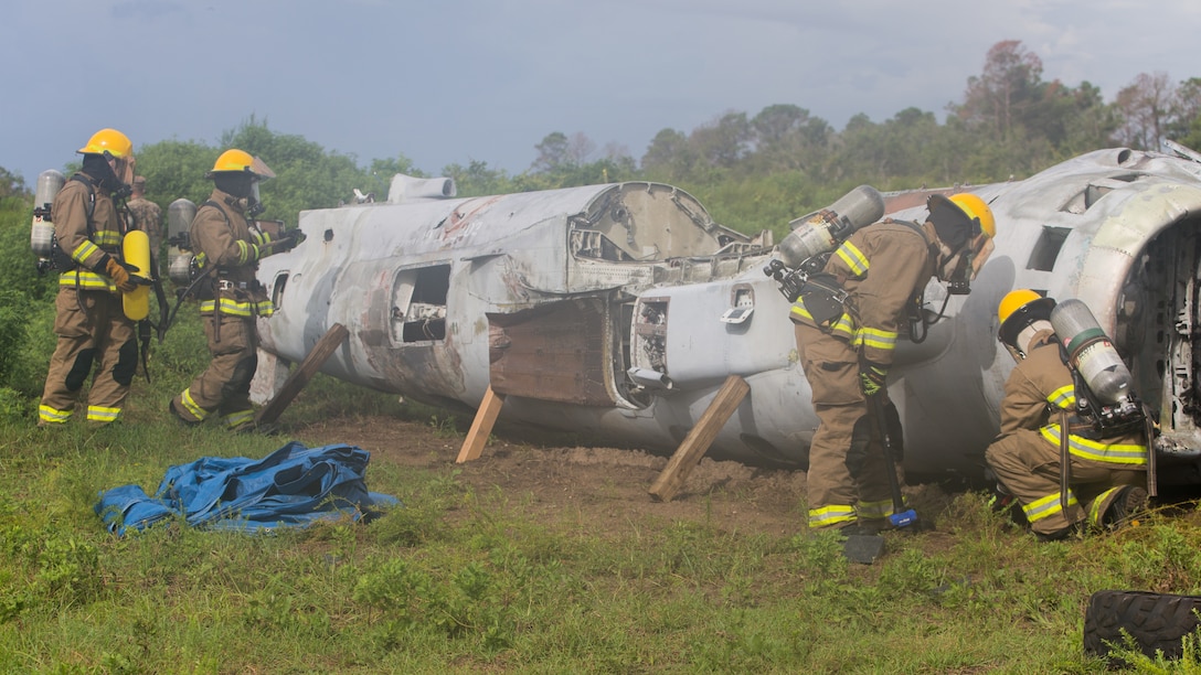 Aircraft Recovery and Fire Fighting (ARFF) Marines inspect a crashed plane for potential hazards during an aircraft recovery scenario at Marine Corps Auxiliary Landing Field Bogue, North Carolina, Aug. 16, 2019. ARFF Marines attached to Marine Wing Support Detachment 273 trained to improve readiness, efficiency, and recovery times.