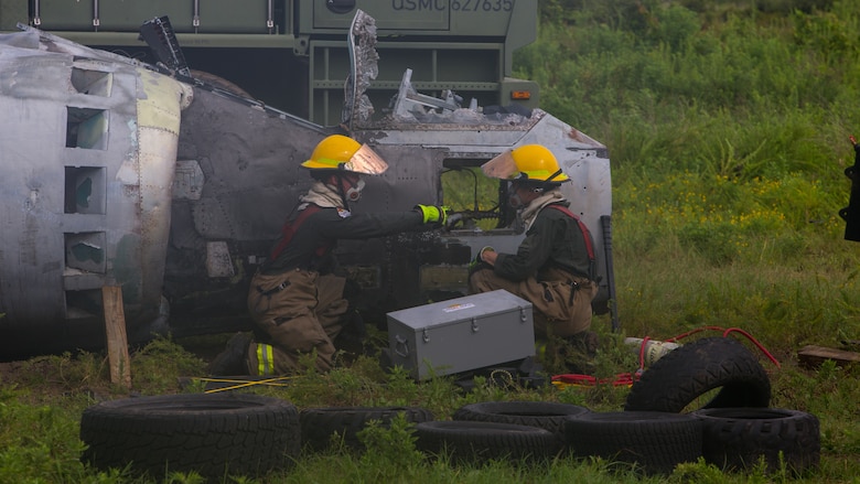 Aircraft Recovery and Fire Fighting (ARFF) Marines assess damage of a crashed plane during an aircraft recovery scenario at Marine Corps Auxiliary Landing Field Bogue, North Carolina, Aug. 16, 2019. ARFF Marines attached to Marine Wing Support Detachment 273 trained to improve readiness, efficiency, and recovery times.