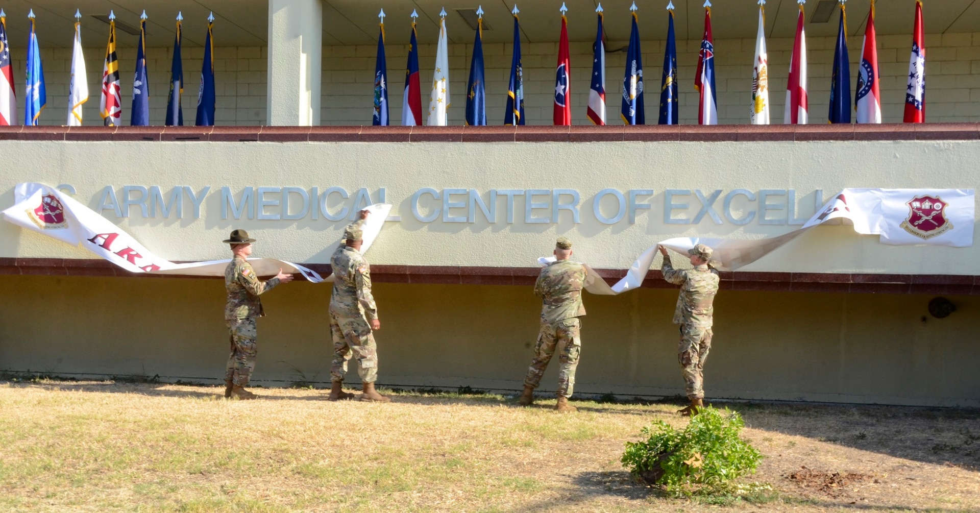 U.S. Army Medical Center of Excellence command team Maj. Gen. Patrick D. Sargent and Command Sgt. Maj. William "Buck" O'Neal were assisted in unveiling the new name by Senior Drill Sergeant Kyle Specht (far left) and Staff Sgt. Alexander Bach, the center’s 2019 Best Warrior winner (far right), at Joint Base San Antonio-Fort Sam Houston Sept. 16.