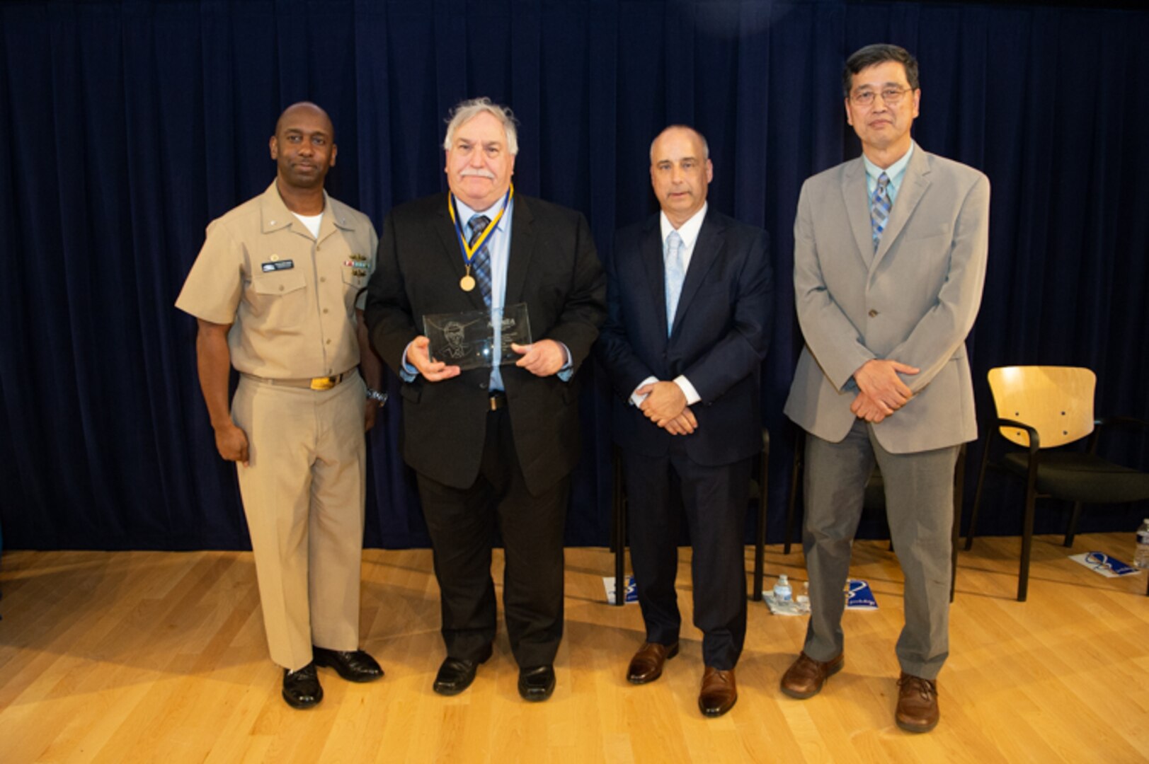 Dr. John Holmes, senior scientific technical manager for underwater electromagnetics, receives the inaugural Dr. Murray Strasberg Award the Naval Surface Warfare Center, Carderock Division Honor Awards on Sept. 10, 2019, in West Bethesda, Md. With Holmes is Commanding Officer Capt. Cedric McNeal, Technical Director Larry Tarasek and Ship Signatures Department Head Dr. Paul Shang. (U.S. Navy photo by Nicholas Brezzell/Released)