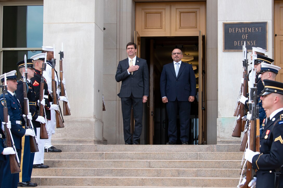 Two men stand at a doorway to the Pentagon.