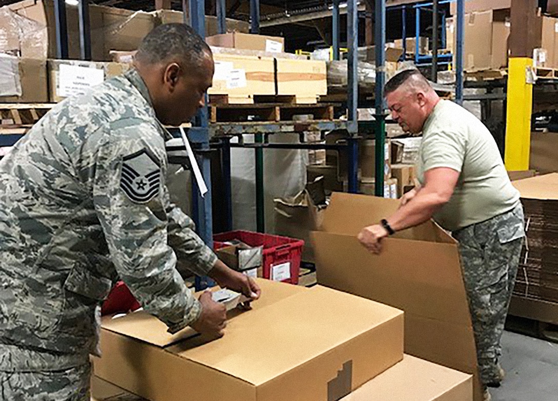 Air Force Master Sgt. Brian Swayne and Army Capt. Garland Fleming II, both DLA Land and Maritime reservists, pack and mark bare items as part of an effort to reduce suspended stock at DLA Distribution warehouses. Courtesy photo