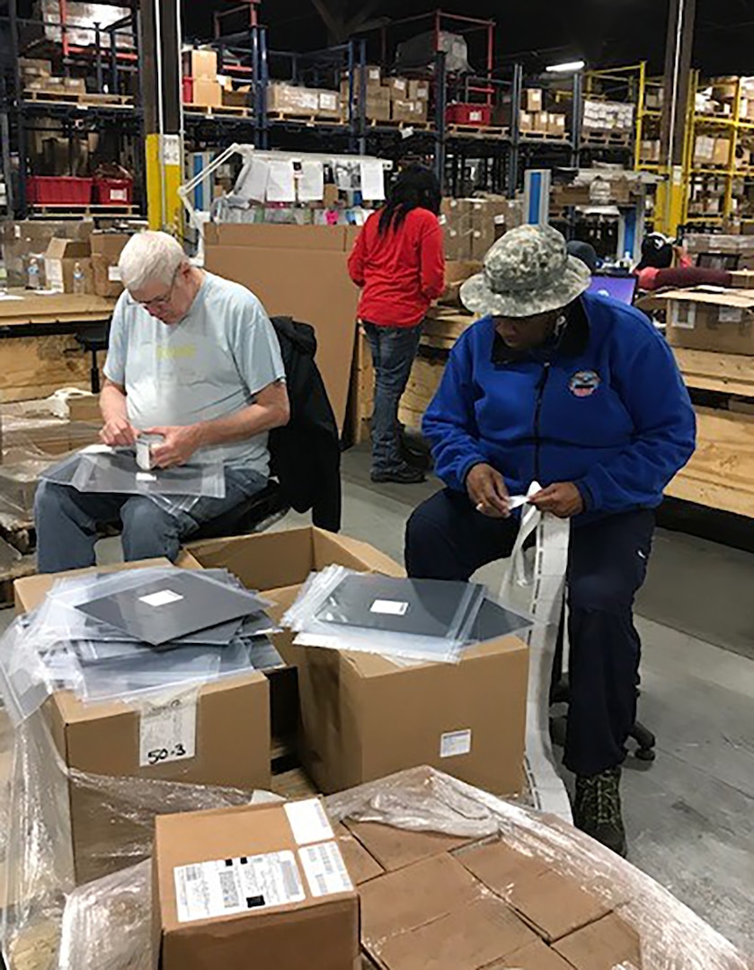 DLA Aviation employees Michael O’Donnell and La Quitta Matthews pack and mark non-compliant material as part of an effort to reduce suspended stock at DLA Distribution warehouses. Courtesy photo