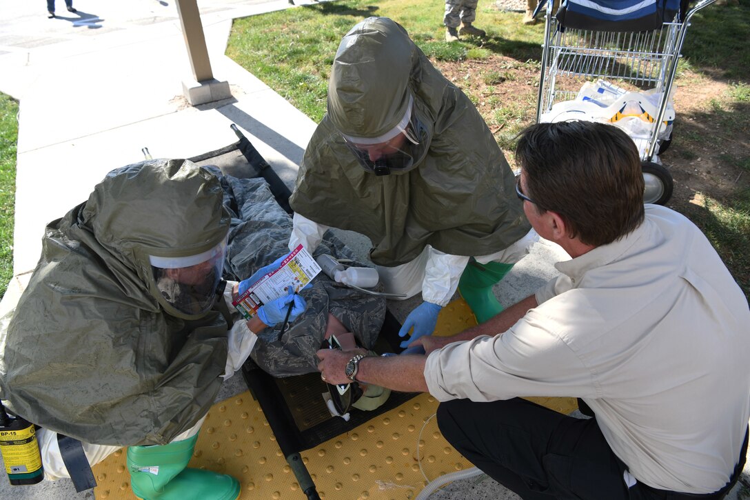 Tom Bocek Sr., a decontamination education training manager, helps Airmen from the 28th Medical Group identify a simulated Chemical, Biological, Radiological and Nuclear threat at Ellsworth Air Force Base, S.D., Sept. 13, 2019. The 28th MDG hosted a decontamination exercise where they demonstrated their ability to administer lifesaving skills by responding to a simulated Chemical, Biological, Radiological and Nuclear threat. This included getting into the appropriate gear, setting up a DECON station, recognizing the presence of chemicals on a training dummy, and cleaning all contaminants off the victim. (U.S. Air Force photo by Senior Airman Thomas Karol)