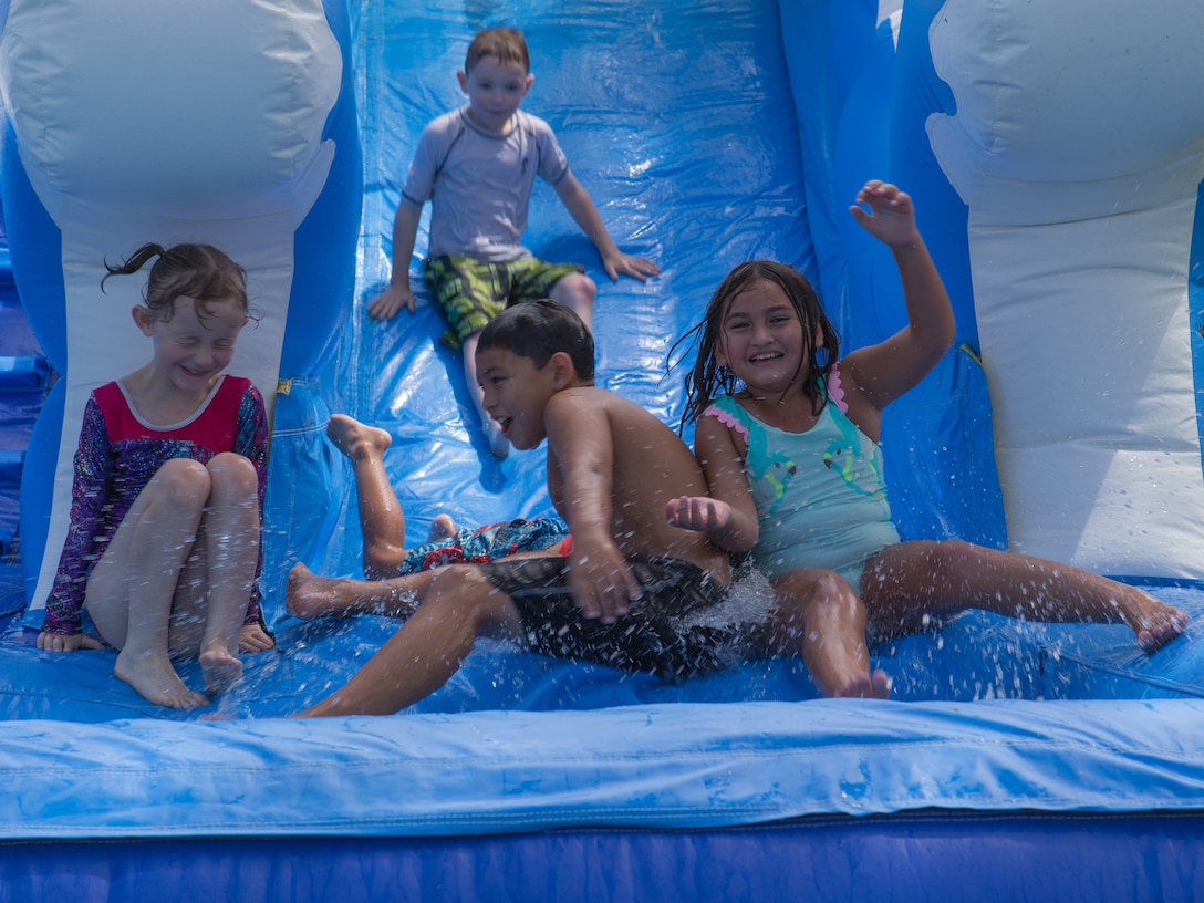 Children race down a water slide during the Marine Wing Headquarters Squadron 2 Family Fun Day at Marine Corps Air Station Cherry Point, North Carolina, August 20, 2019. The MWHS-2 Family Fun Day was hosted to give Marines and Sailors an opportunity to socialize and build camaraderie throughout the unit.  (U.S. Marine Corps photo by Pfc. Steven Walls)