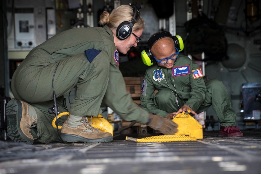 An airman shows parts to a child inside an aircraft.