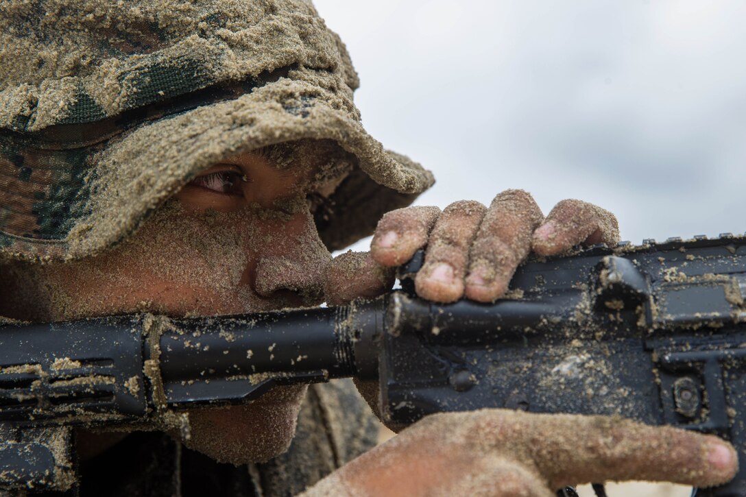 A close up of a sand-covered Marine with a rifle.