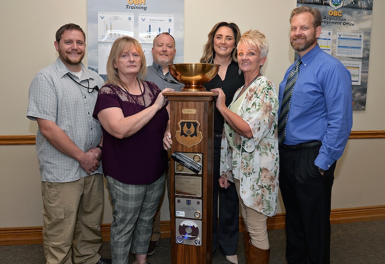 Britt Bush, Joan Young, Jacob Beyer, Brittney Starnes, Michelle Broderick and Benjamin Orton, Business Operations Workloading Chief, pose with the Ogden Air Logistics Complex L-A-M-P Award trophy Sept. 10 at Hill Air Force Base, Utah.
