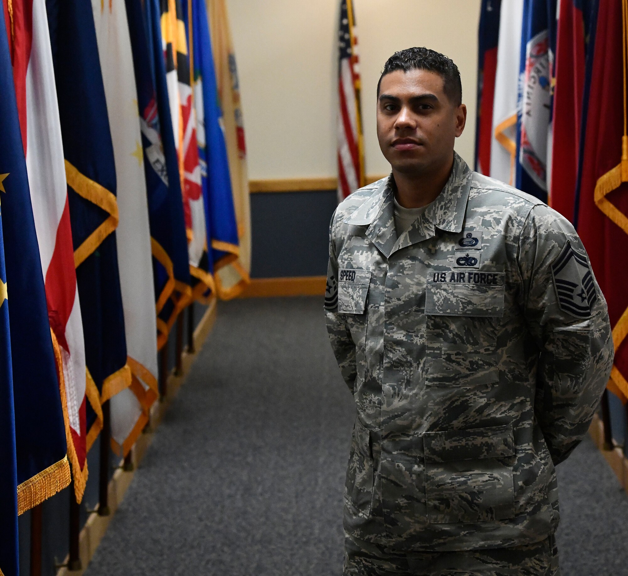 Senior Master Sgt. Calvin Speed, the Air Force Materiel Command training manager, stands next to the flags that he protects at AFMC headquarters, Wright-Patterson Air Force Base, Ohio. (U.S. Air Force photo / Darrius A. Parker)