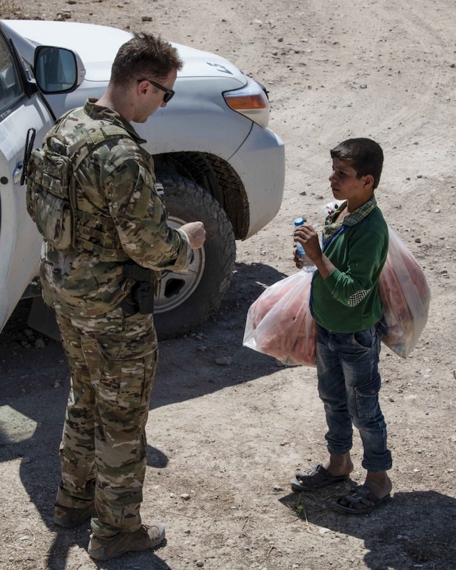 A service member speaks to a child.