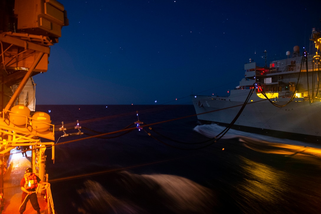 Two ships float next to each other at night.