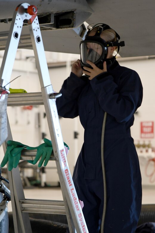 a photo of an airman prepping his gas mask before entering the fuel tank of an A-10