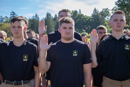 A group of young teenage men and women raise their right hands.